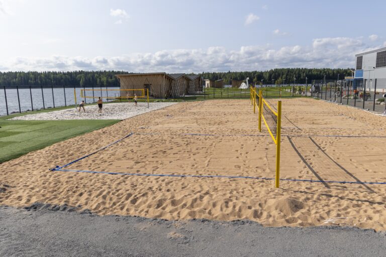 Beach volley kenttiä viisi kuvassa järven rannalla.