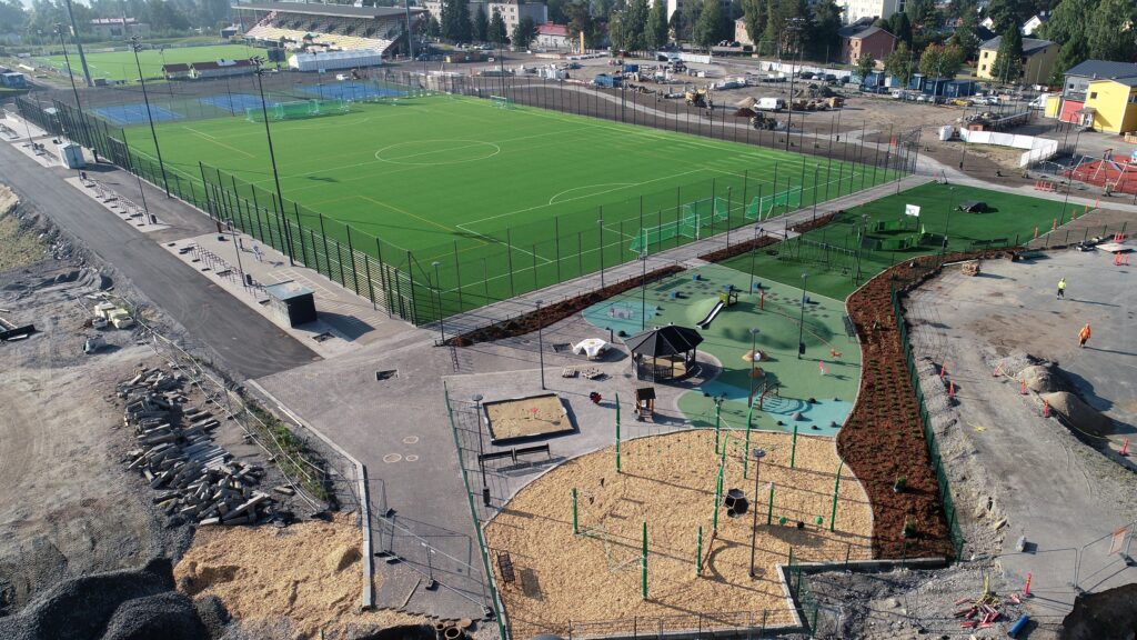 Etualalla leikkikenttä, kuvassa keskellä uusi jalkapallokenttä ja taustalla jo rakennettu stadion.