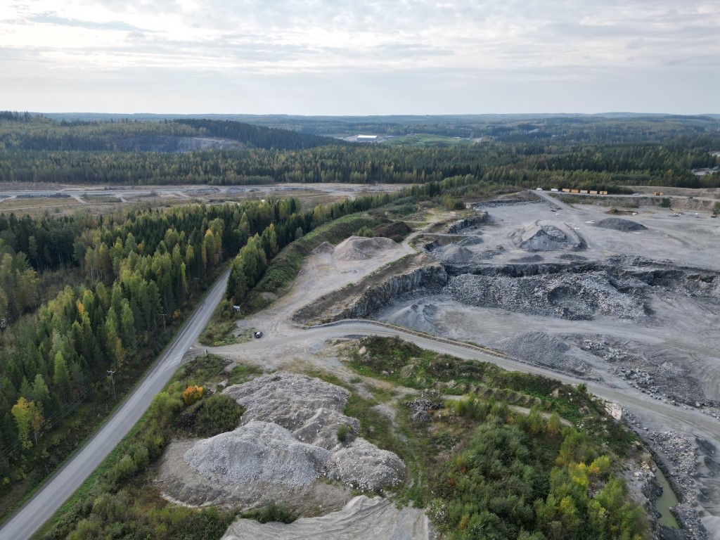 Ilmakuvassa tie, metsää sekä maa-aineskasoja.