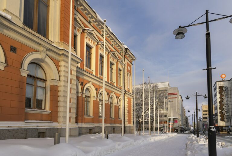 Vasemmalla näkyy osa kaupungintalosta sekä luminen katu sen edessä.