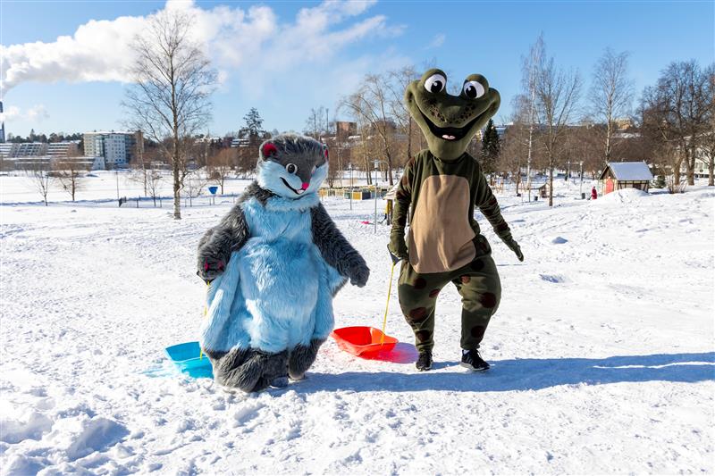 Maskotit liito-orava Pähkä ja sammakko Kamu talvisessa maisemassa Kuopion Brahenpuistossa