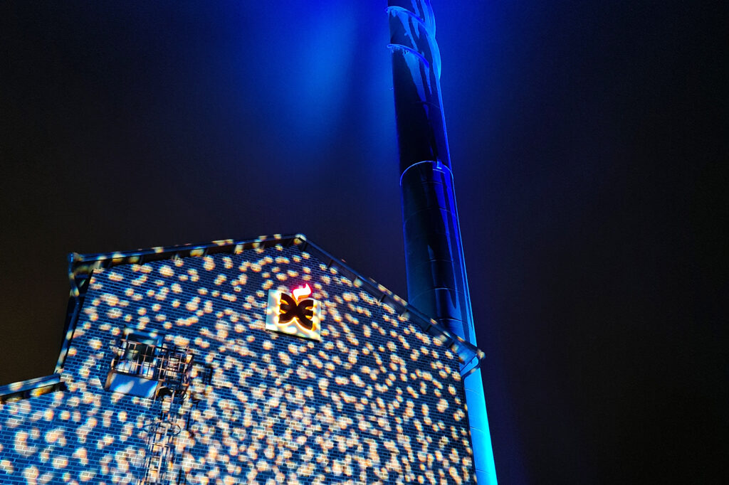 Lämpökeskuksen seinä valaistu sinisellä ja lukuisilla vaaleilla valopalloilla.