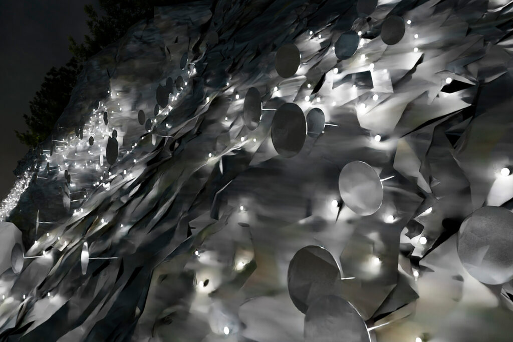 Havainnekuva Pulssi-nimisestä taideteoksesta, missä on paljon rytmissä tuikkivia valoja kiinnitettynä kallioseinämään.