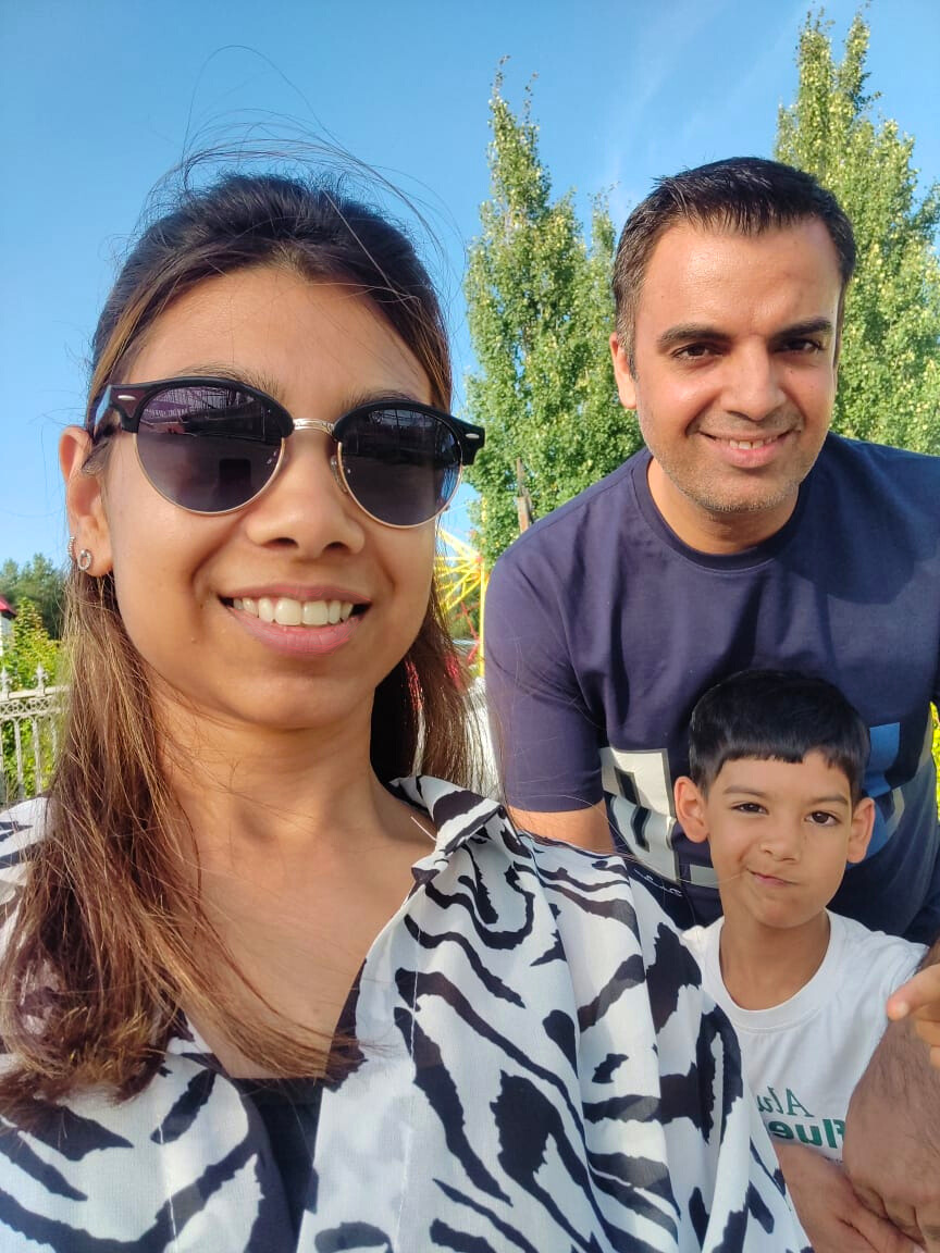 A family of a mom, dad and a son are smiling to the camera.