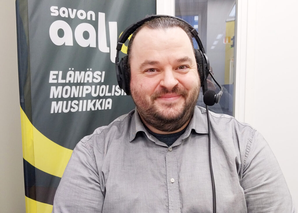 A bearded man is waiting for the radio broadcast to start, wearing headphones.